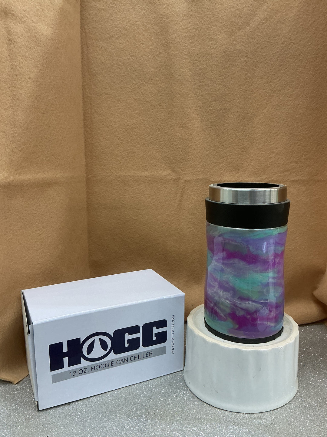 Pastel insulated tumbler with purple, blue, and green marbled design, black lid, on a white stand, with a Nancy’s Designs branded box nearby.