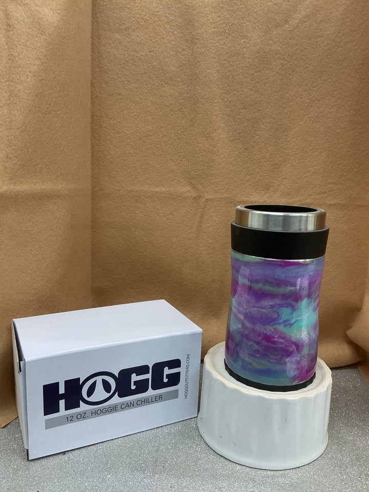 Pastel-colored tumbler with a stainless steel rim, placed on a white stand, next to a white box labeled "HOGG" by Nancy’s Designs.