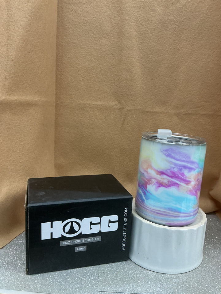 Shortie tumbler with a colorful, marbled design in pastel shades, placed on a white stand next to a black Nancy’s Designs box.