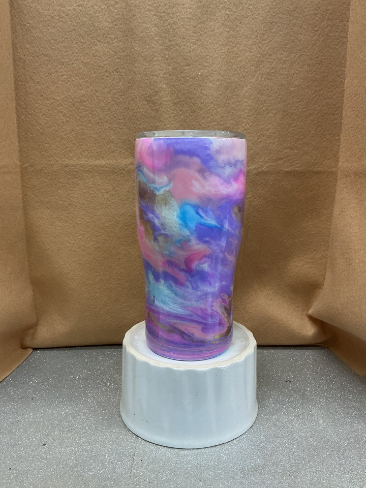 Hand-painted ceramic vase with dark pastel swirls in pink, purple, blue, and gold, displayed on a white pedestal against a brown background.