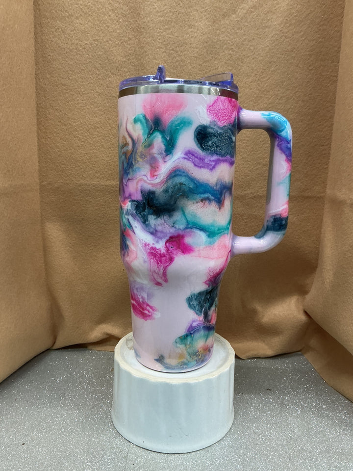 Big Swig tumbler with a colorful marbled design in pink, blue, purple, and black, featuring a clear lid and handle, by Nancy’s Designs.