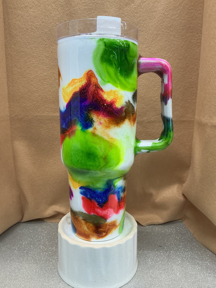 Travel tumbler with colorful abstract swirl design, clear lid, and handle, by Nancy’s Designs, on a white base.
